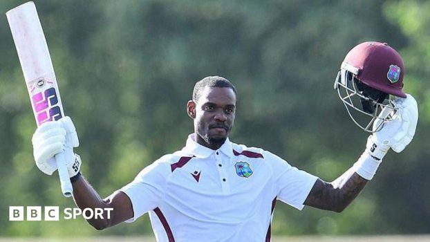 Justin Greaves holds his bat and helmet aloft after reaching 200