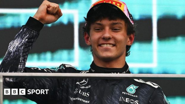Kimi Antonelli smiles and clenches his fist in celebration on the podium after winning the Japanese Grand Prix