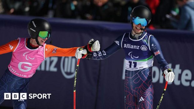 James Hannan and Fred Warburton bump fists after crossing the finish line of the downhill at the Winter Paralympics