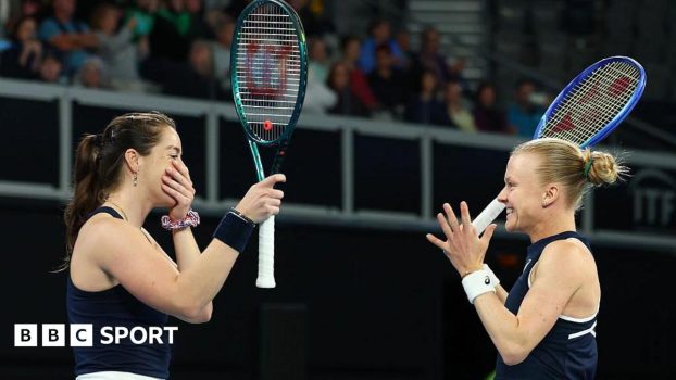Jodie Burrage (left), in a dark blue vest with her racket raised in her right hand and her left hand over her mouth, and a smiling Harriet Dart (right), in a dark blue vest with both hands raised, approach each other to celebrate their win.