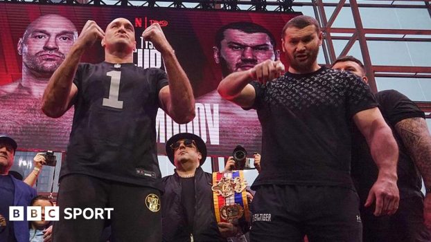 Tyson Fury puts up his fists as Arslanbek Makhmudov points to the camera