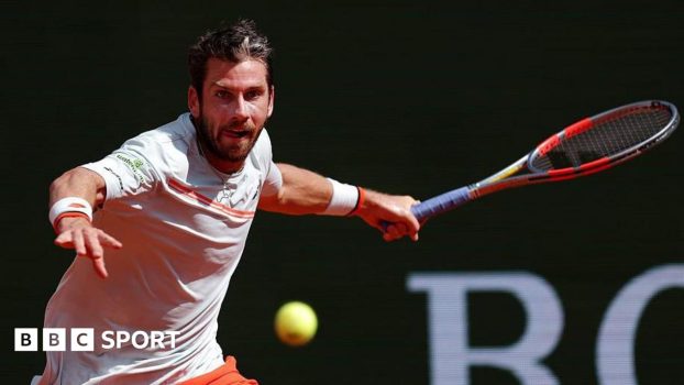 Cameron Norrie, in largely white T-shirt with orange trim, plays a forehand at the Monte Carlo Masters on Sunday
