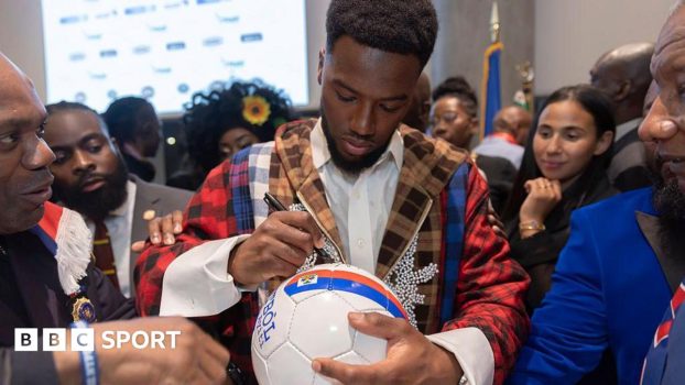 Duckens Nazon signs a football