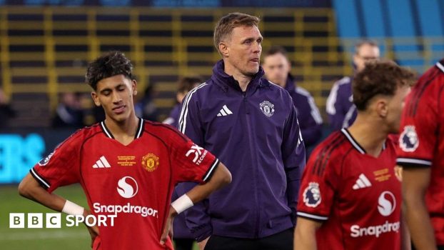 Manchester United Under-18 coach Darren Fletcher, in purple tracksuit top, stands between two of his players, who both wear red match kit